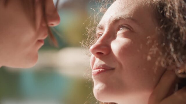 Caucasian woman smiling up at partner by lake sunlight, young poet and partner share quiet affectionate moment after kiss, gentle hand at nape, hopeful gaze toward future family and marriage plans