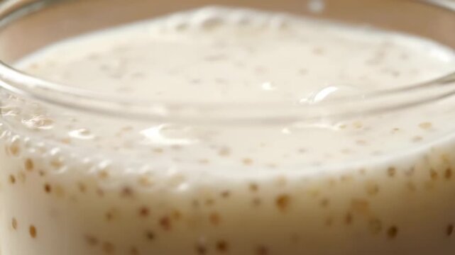 Creamy millet milk close-up with smooth texture and frothy surface in glass bowl for healthy beverage concept