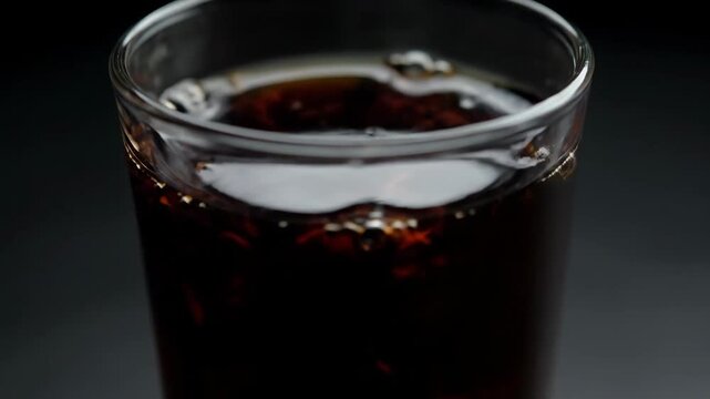 Refreshing Indian nannari sharbat drink in glass with ice and herbs slow motion macro close-up dark moody lighting