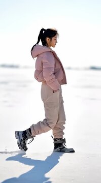 Una joven camina con elegancia a trav&eacute;s de un paisaje nevado, envuelta en un abrigo rosa pastel.