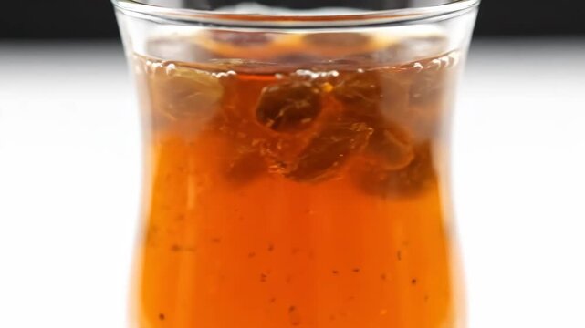 Macro close-up of turkmen raisin compote drink slow rotating reveal with amber liquid texture