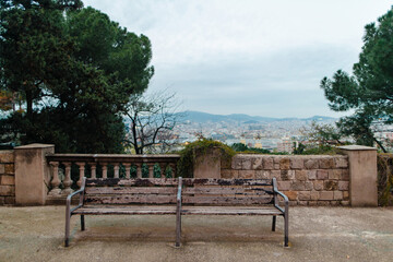 Fototapeta premium Weathered park bench offers panoramic view of Barcelona cityscape