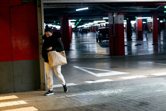 Woman walking through parking garage using phone