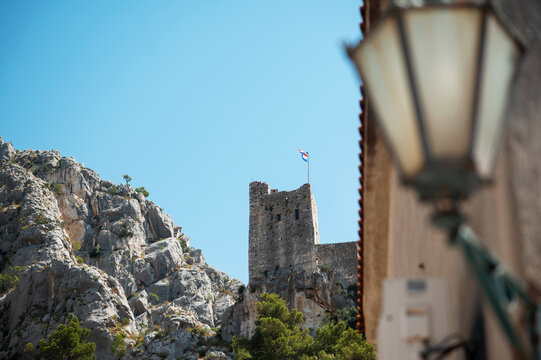 Omis fortress ruins perched on a rocky cliff under a clear blue sky