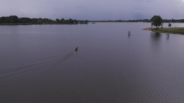 Vientiane, Laos - August 27, 2025: Fisherman riding a small fishing vessel across the lake near Vientiane.