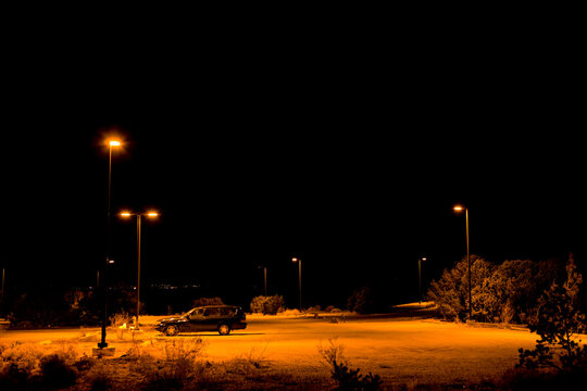 A single car parked under lights in a car park in Santa Fe and night.