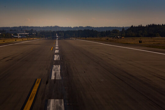 View down an airport runway, an aircraft preparing for take off.