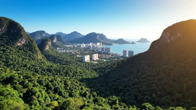 Scenic aerial view of tropical coastal town nestled between lush green mountains and sparkling ocean waters under a clear blue sky