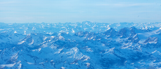 Obraz premium Plane view of mountains at sunrise, snow rock and blue cloudy sky aerial view