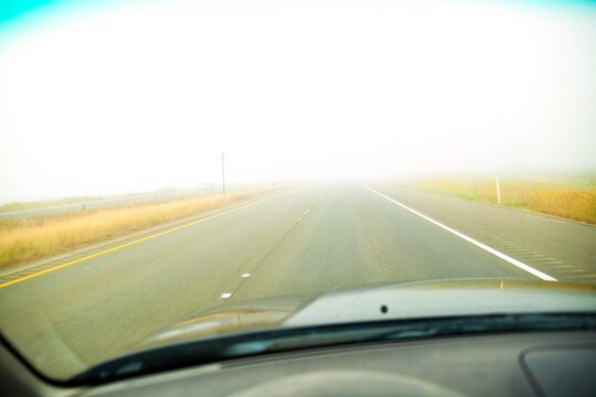 A driver's view of the road ahead with thick fog across the road, limited visibility,.