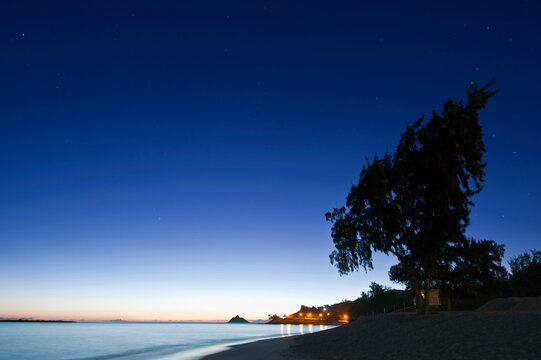Oahu, Lanikai Beach at dawn, lightening sky on the horizon, beach and palm trees.
