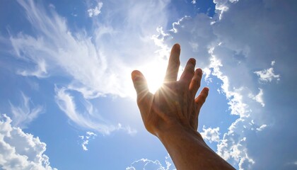 Hand reaches towards bright sun shining through fluffy clouds in blue sky, seen from low angle