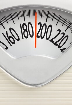 Analog bathroom scale with red needle pointing near 200 pounds. Health, weight tracking, and fitness concept with clean design.