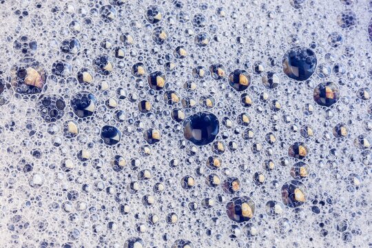 Macro view of tightly packed soap bubbles showing detailed surface tension and tiny reflections