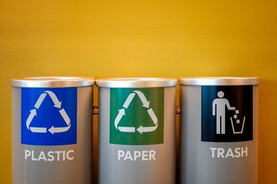 Color-coded bins for plastic recycling, paper recycling, and general trash disposal, promotes sustainability