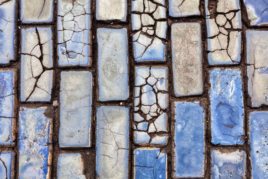 A close-up view of cracked blue cobblestones lining the historic streets of Old San Juan, blue glazed bricks or adoquines used as ballast for shipping in the colonial era. 