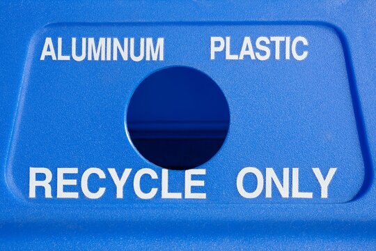 Close-up of a blue recycling bin marked for aluminum and plastic with a circular opening.