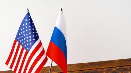Two national flags stand on a table representing the USA and Russia in a simple setting