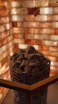 Electric sauna heater with glowing hot stones, surrounded by walls lined with therapeutic rock salt for a healing, steamy atmosphere.