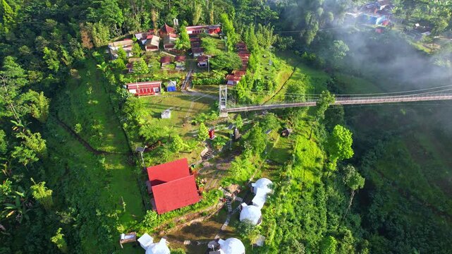 Aerial drone footage of a campsite glamping spot, nearby the main road leading to B29 summit in Bromo, with a metallic bridge, trees, in Senduro area, Lumajang regency, Java island, Indonesia