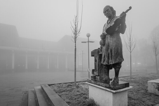 Antonio Stradivari statue holding a violin in Piazza Marconi, Cremona, Italy, on a heavily foggy day, bringing an atmospheric and mysterious mood to the iconic monument