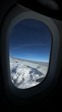 Passenger&rsquo;s view from airplane window soaring above clouds and majestic mountain landscapes&mdash;stunning scenery, peaceful sky, and awe-inspiring altitude