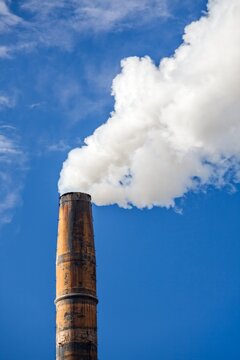 Industrial smokestack releasing white smoke against a clear blue sky in Port Angeles, Washington.