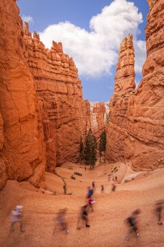Hikers explore the Navajo Loop Trail winding through towering hoodoos in Bryce Canyon. A dynamic scene of motion and natural wonder in Utah red rock landscape.