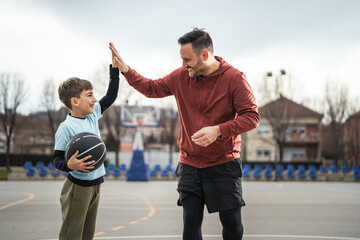 Father and son high-five playing basketball outdoors
