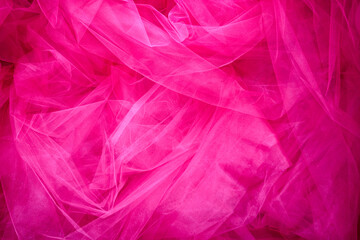 Fototapeta premium Expressive elegance and femininity captured in a vibrant pink tulle background. The delicate folds of lightweight mesh fabric create a rich, dreamy texture perfect for festive designs.