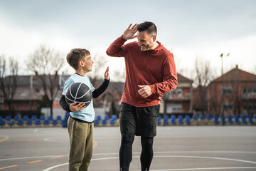 Fototapeta premium Father son enjoying conversation on outdoor basketball court
