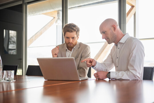 Business colleagues discussing project on laptop during meeting