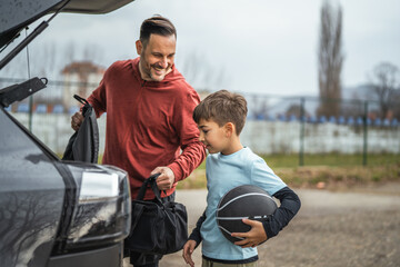 Naklejka premium Father and son packing bags for basketball practice