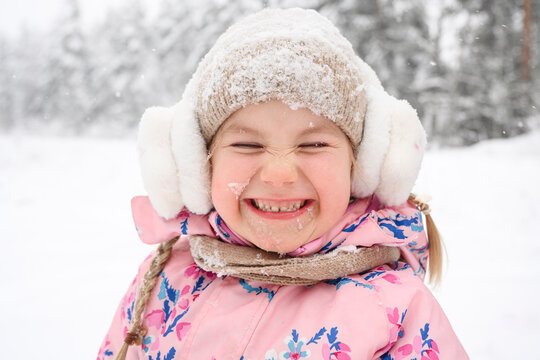 Happy child smiling outdoors in winter snow wearing earmuffs