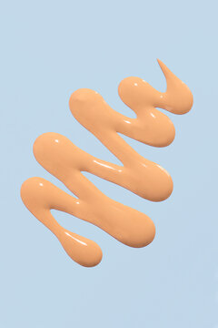 Liquid foundation swatch on blue background with copy space