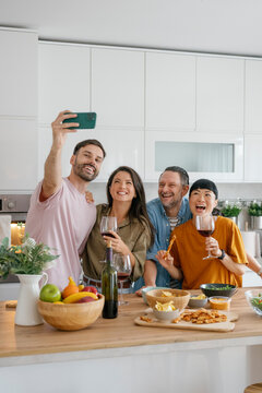 Friends taking selfie and laughing together at dinner at home