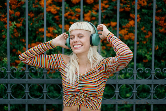 Happy hipster woman with headphones smiling outdoors