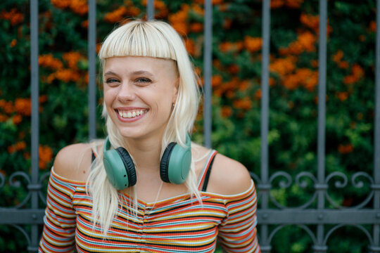 Happy hipster with headphones smiling outdoors looking at camera