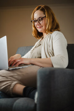 Professional using laptop for remote work while sitting in armchair