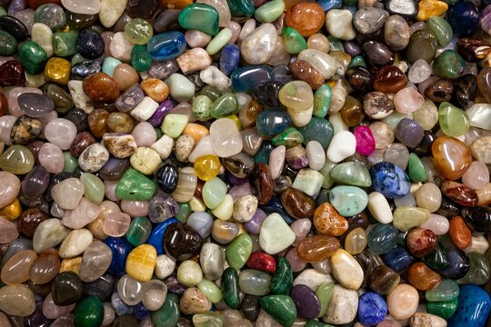 Close view of a large collection of colorful polished stones filling the frame, showing smooth textures and natural patterns.