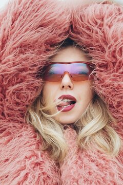 Fashion portrait with sunglasses and pink fur coat outdoors