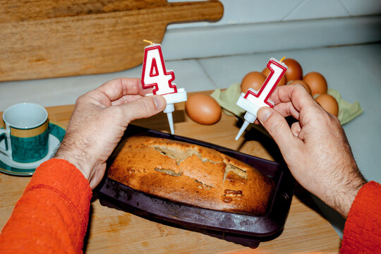 Placing birthday candles on homemade lemon cake in kitchen