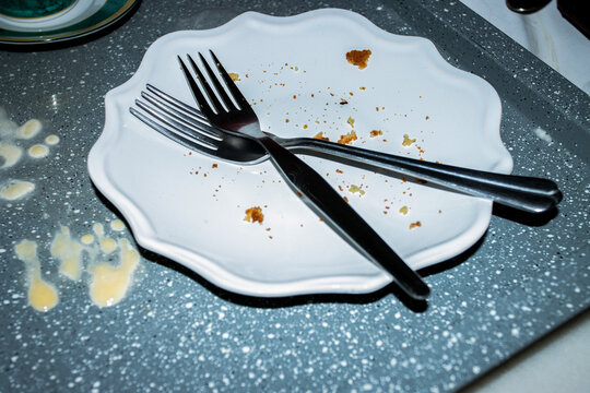 Empty dirty plate with crumbs and cutlery after meal on table