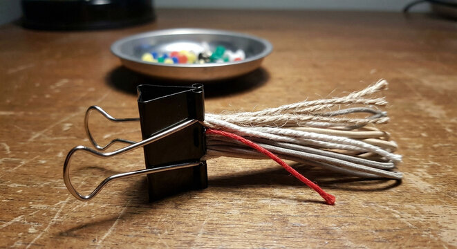 Binder clip bundling string ends on wooden desk planning concept