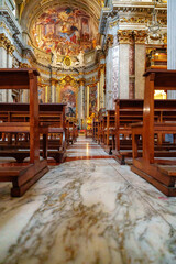 Naklejka premium Views of wooden benches and marble floor in a large church with high ceiling and artwork