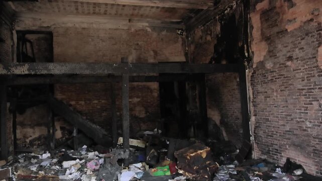 Fire marshal inspecting charred structural elements and debris