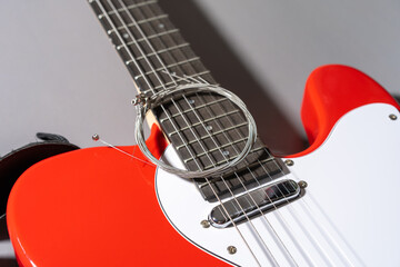 Close-up of a red electric guitar with white pickguard, chrome hardware, dual pickups, bridge saddles, and a coiled set of new metallic strings resting on the body.
