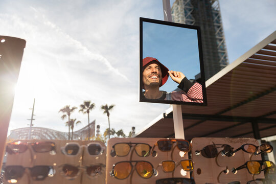 Smiling person reflected in mirror at flea market with sunglasses