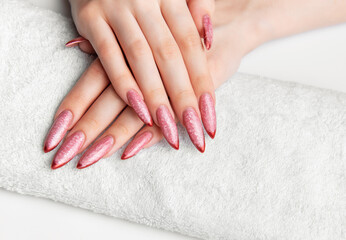 Naklejka premium Woman's hands resting on towel with pink stiletto nails