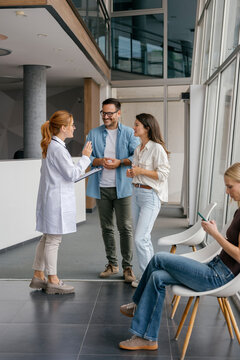 Doctor talking with patient and companion in clinic waiting room